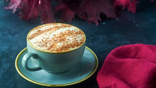 A light green cup and saucer with frothy milk